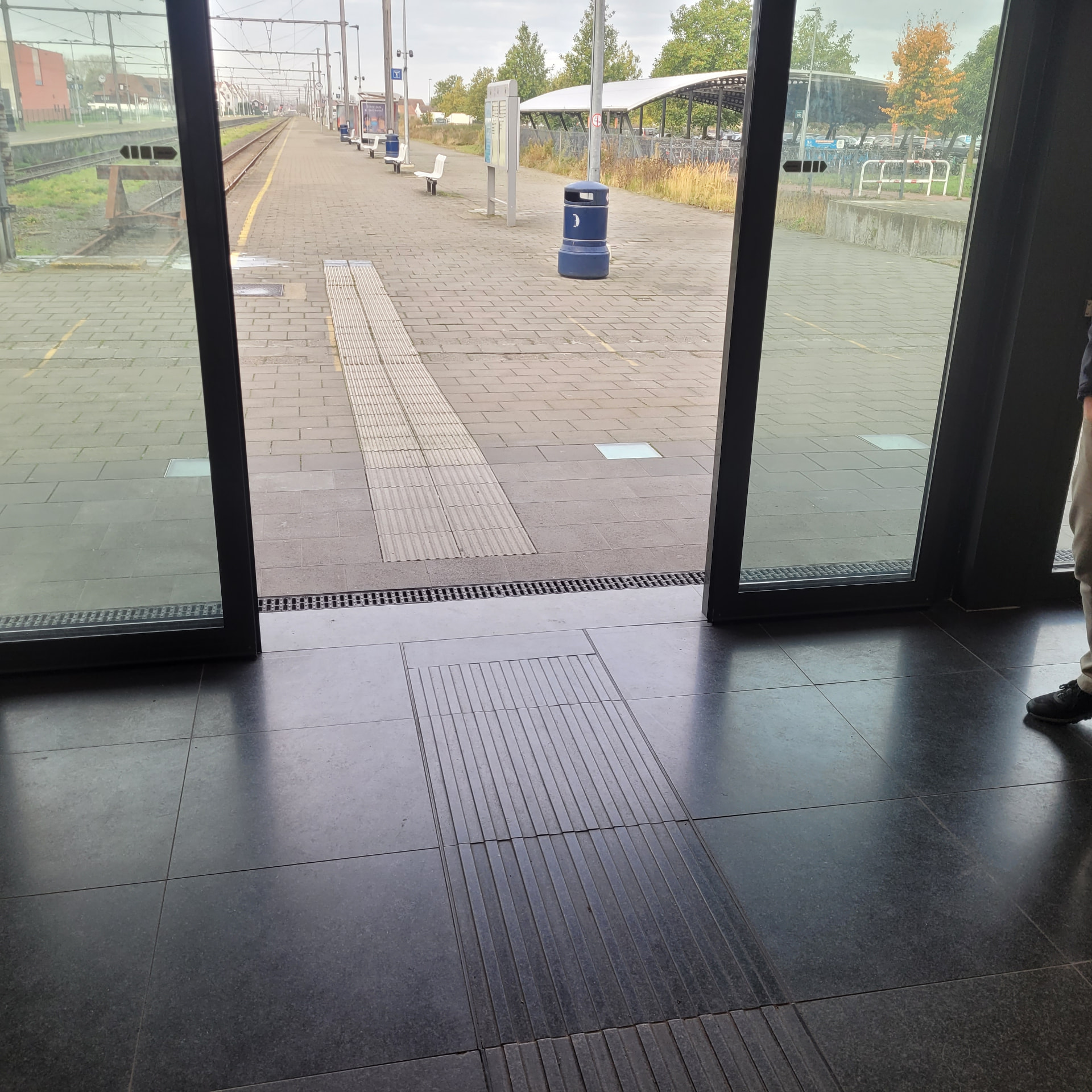 Geleidetegels in natuursteen tussen een wachtruimte en het perron.