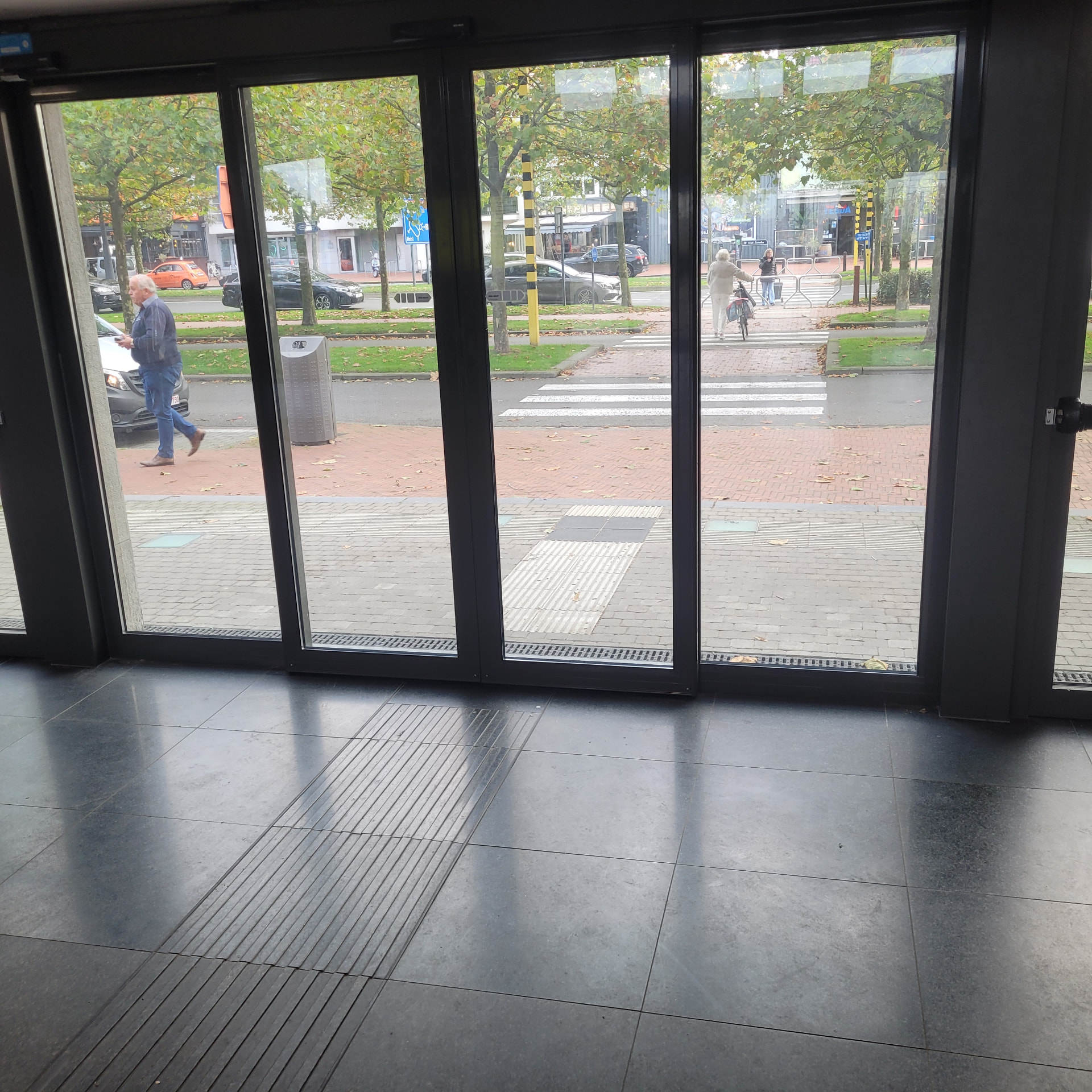 Geleidetegels in natuursteen aan een stationsingang.